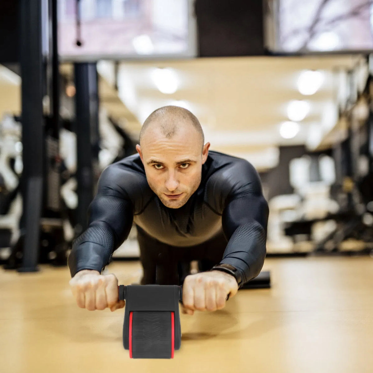 Man performing an ab roller rollout in a gym